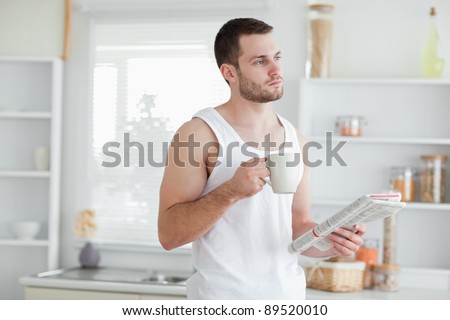 Dreaming man drinking tea while reading the news in his kitchen