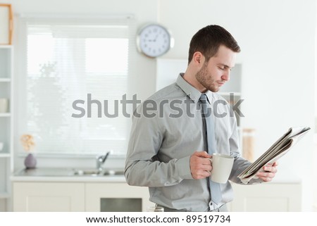 Young businessman reading the news while having breakfast in his kitchen