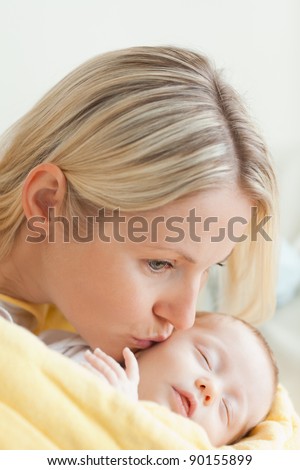 Affectionate young mother kissing her sleeping baby's cheek