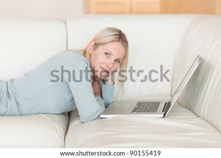 Side view of young woman with laptop lying on the couch