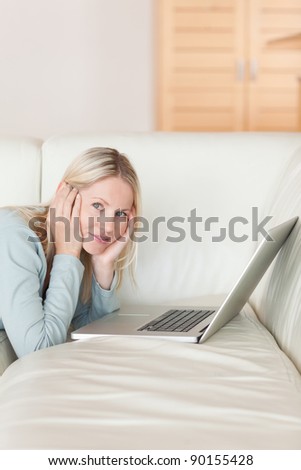 Side view of young woman lying on the couch surfing the web