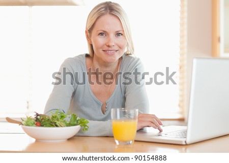 Young woman having healthy lunch while working on her notebook