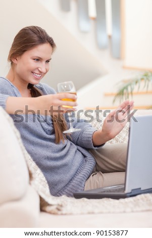 Portrait of a woman having a glass of white wine during a video conference in her living room