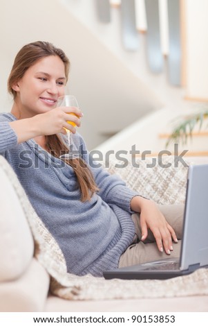 Portrait of a woman having a glass of wine during a video conference in her living room