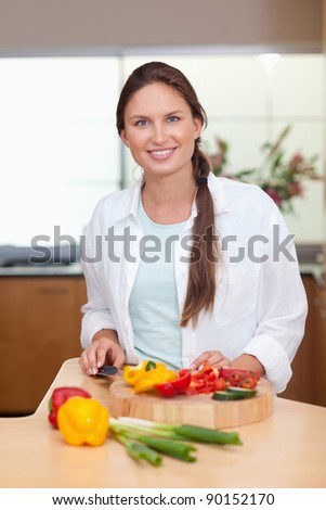 Portrait of a lovely woman slicing a pepper in her kitchen