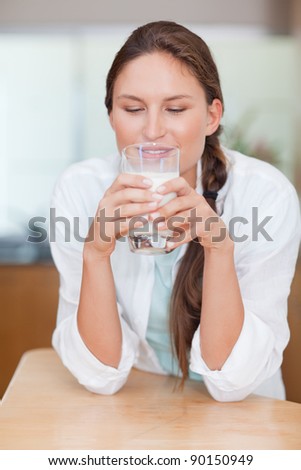 Portrait of a young woman drinking milk in her kitchen