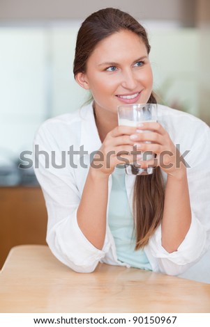 Portrait of a calm woman drinking milk in her kitchen