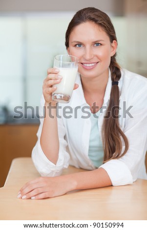 Portrait of a glowing woman drinking milk in her kitchen