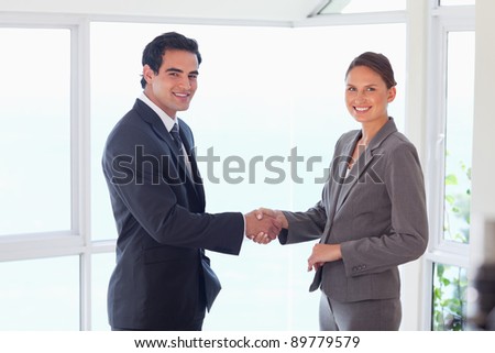 Side view of smiling young trade partner shaking hands
