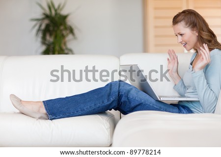 Excited young woman on the sofa waiting for online auction to be over
