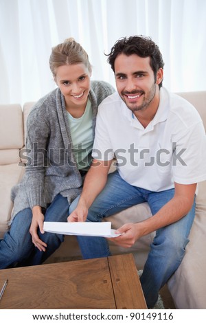 Portrait of a happy couple reading a letter in their living room