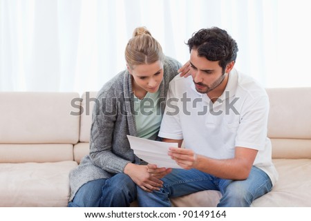 Focused couple reading a letter in their living room