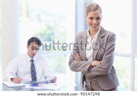 Smiling businesswoman posing while her colleague is working in a meeting room