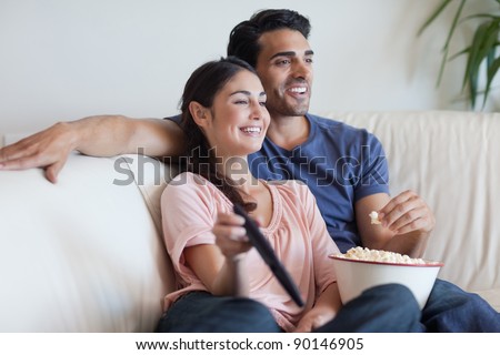 Couple watching TV while eating popcorn in their living room