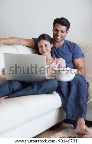 Portrait of a couple watching a movie while eating popcorn with a laptop