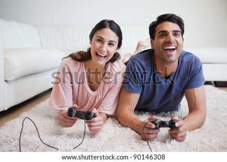 Playful couple playing video games in their living room