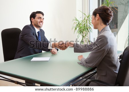 Smiling manager interviewing a good looking applicant in his office