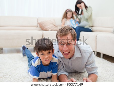 Dad and son lying on the carpet with mom and daughter behind them