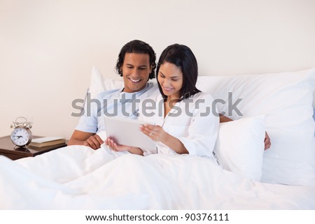 Young couple surfing the internet on the bed