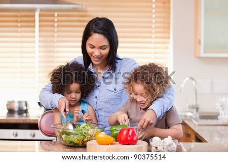 Young mother and daughters preparing salad in the kitchen together