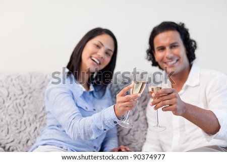 Young couple celebrating with sparkling wine on the couch