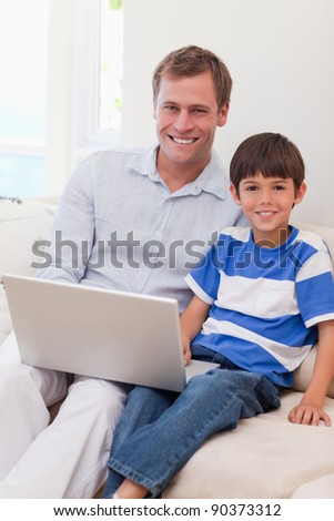 Smiling young father and son surfing the internet together