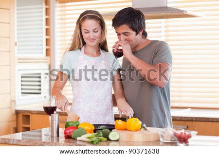 Young couple cooking dinner while drinking red wine in their kitchen