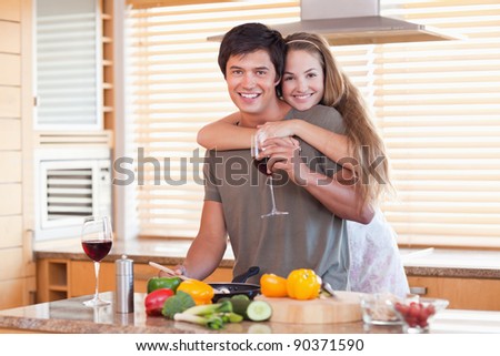 Lovely couple drinking red wine while hugging in their kitchen