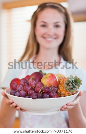 Portrait of a woman presenting a fruit basket in her kitchen