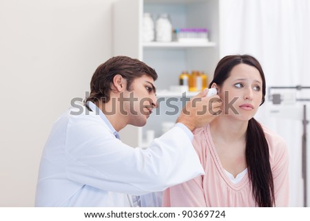 Male doctor examining his female patients ear