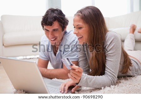 Young couple lying on the floor with laptop booking holidays