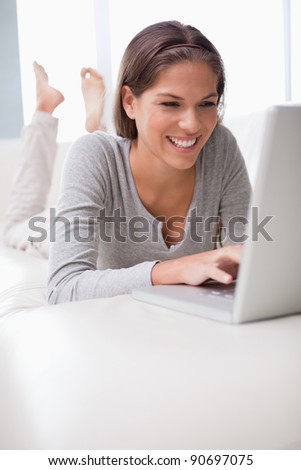 Smiling young woman chatting online on her sofa