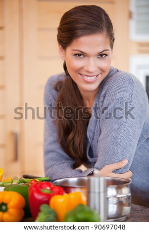 Smiling young woman leaning against the kitchen counter