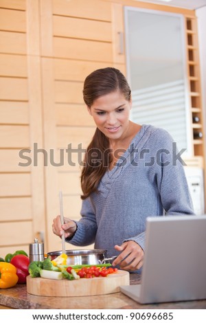 Young woman reading off a recipe while cooking