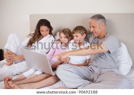Family using a laptop in a bedroom