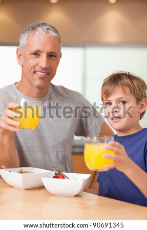 Portrait of a cute boy and his father having breakfast in a kitchen