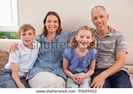 Family sitting on a sofa while looking at the camera