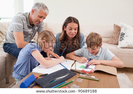 Parents helping their children to do their homework in their living room