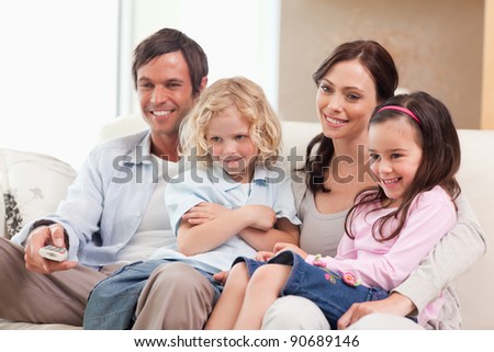 Smiling family watching television together in a living room