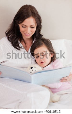 Portrait of a mother reading a story to her daughter in a bedroom