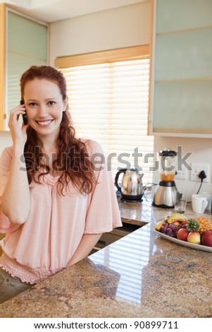 Smiling woman on the phone next to the kitchen counter