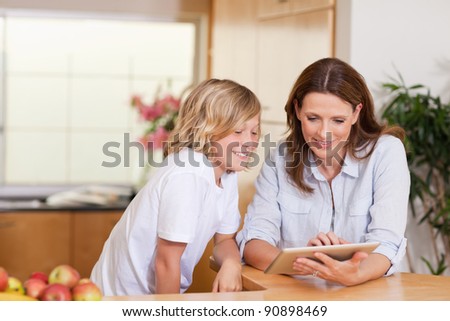 Woman and son using tablet in the kitchen together
