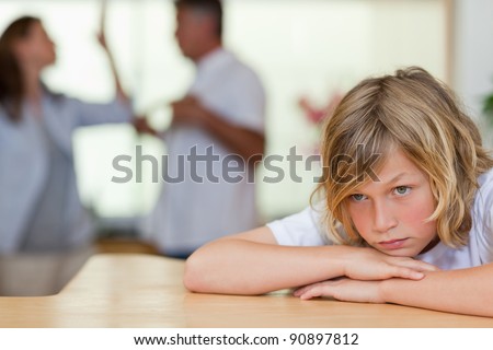 Worried looking boy with his fighting parents behind him