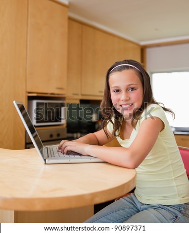 Girl with her laptop sitting at the kitchen table