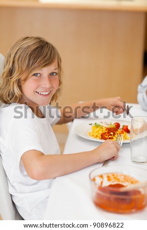 Side view of happy smiling boy sitting at the dinner table