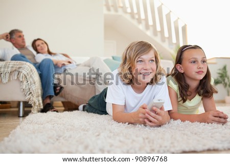 Siblings lying on the carpet watching tv together