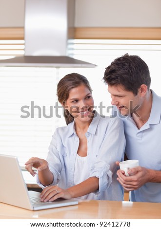 Portrait of a couple using a laptop while having tea in their kitchen