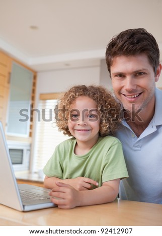 Portrait of a boy and his father using a notebook in their kitchen