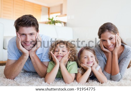 Family lying on a carpet in their living room