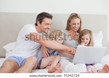 Family using notebook together on the bed
